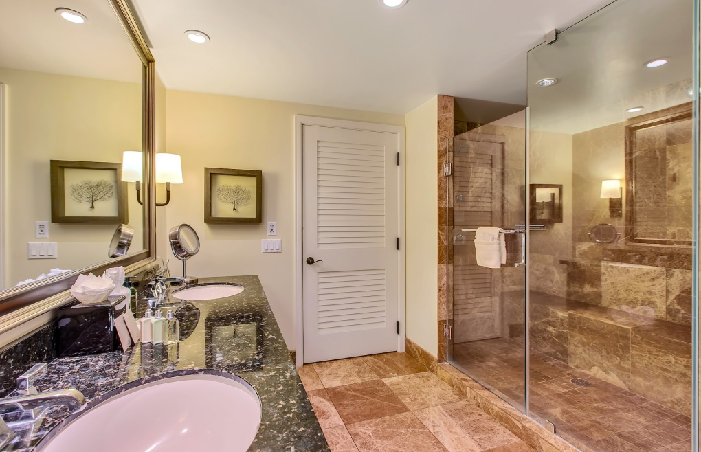 With a glass and marble walk-in shower and a double granite vanity